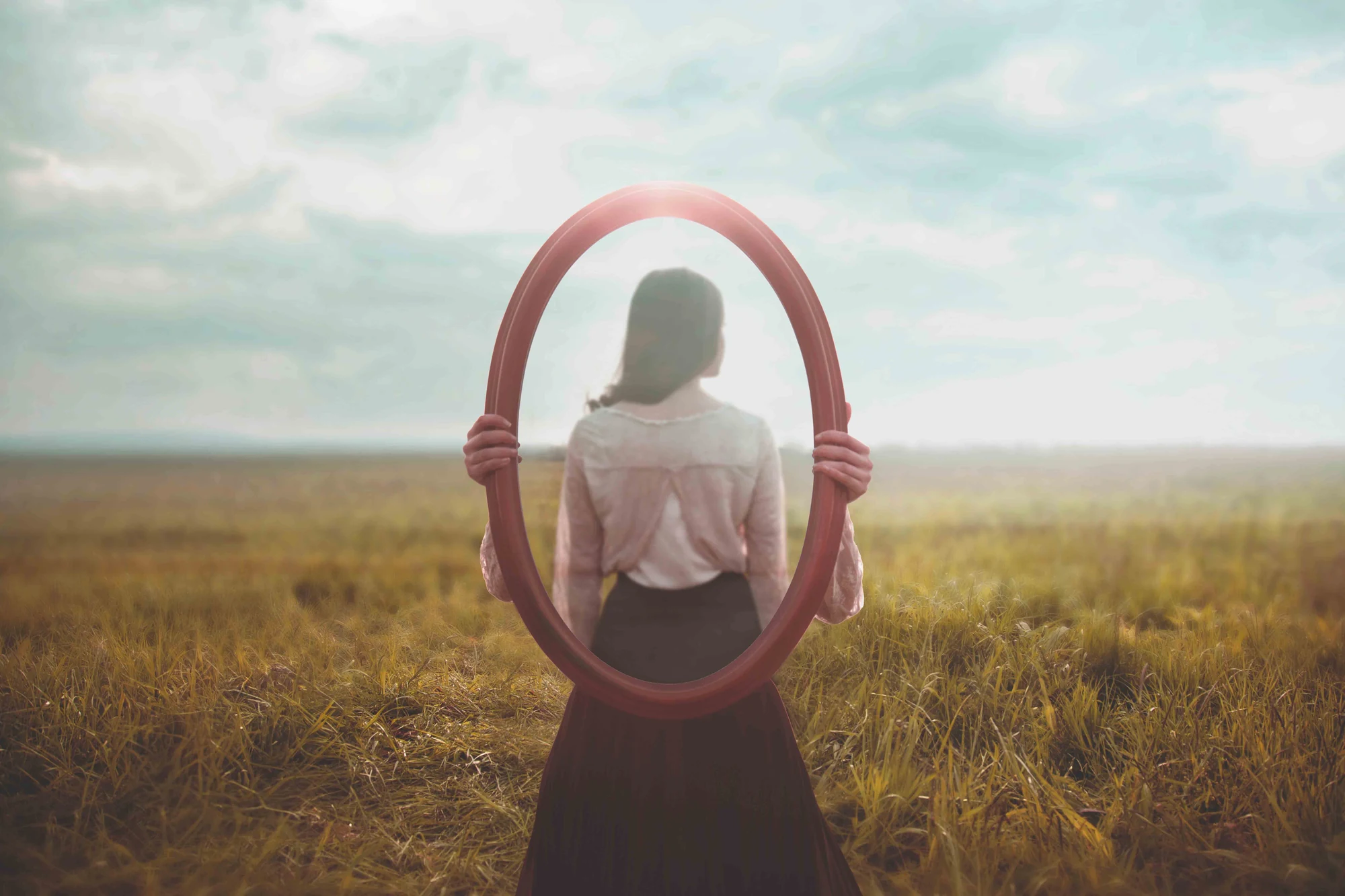 Woman holding a mirror in an open field
