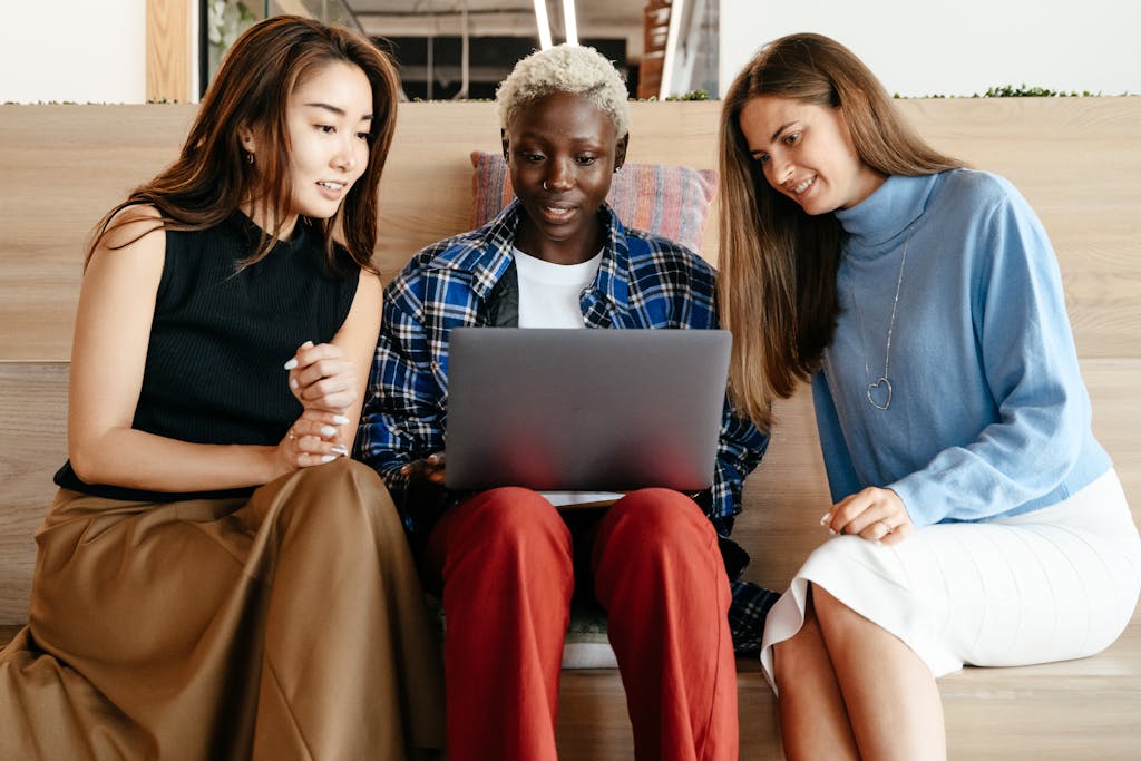 Cheerful multiethnic colleagues using laptop together